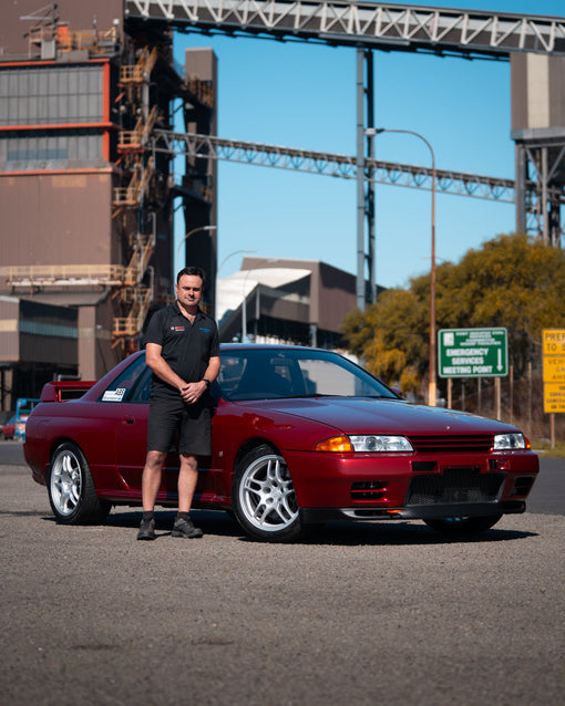 Owner standing with his red Nissan Skyline R32 GT-R fitted with Bosch Motorsport electronics, Newcastle industrial backdrop