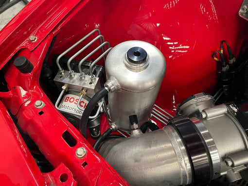 Bosch Motorsport ABS M5 hydraulic unit plumbed with brake hardlines beside an alloy reservoir in a red engine bay