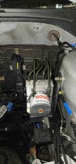 Bosch Motorsport ABS M5 hydraulic unit on its 909 bracket in a Mitsubishi EVO 7-9 engine bay with formed brake hard lines