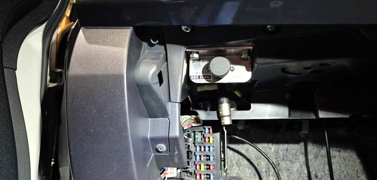 Bosch ABS diagnostic port mounted on a 909 plate in the glovebox corner of a Mitsubishi Lancer EVO X