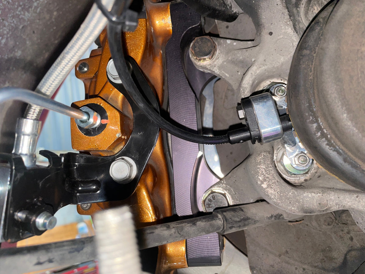 Bosch DF11 wheel speed sensor and 909 billet mount installed at the rear hub of a Nissan Skyline GT-R R33, outboard tone ring behind the two-piece rotor
